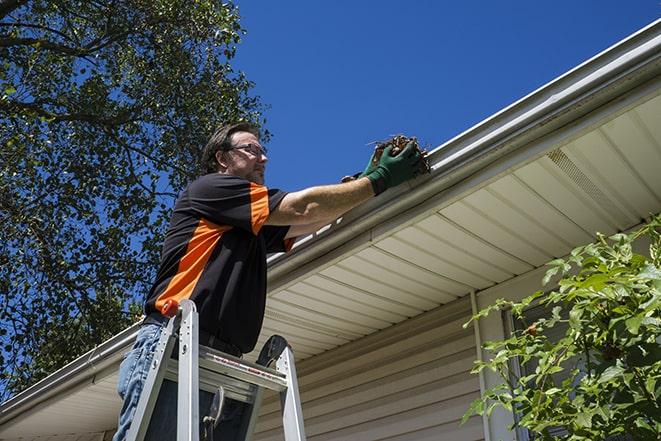 skilled worker repairing damaged gutter with tools in Davison MI